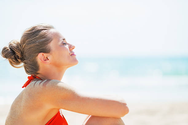portrait of happy young woman relaxing on beach stock photo