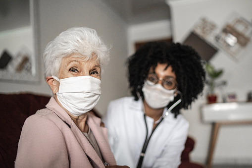 Portrait of health visitor and a senior woman during home visit