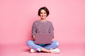 Portrait of her she nice attractive lovely charming pretty cute cheerful cheery, brown-haired girl sitting in lotus pose using laptop typing e-mail isolated over pink pastel color background