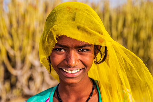 Indian young girl resting on a sand dune - desert village, Thar Desert, Rajasthan, India.