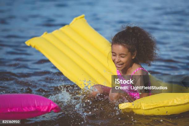 portrait of laughing african american girl having fun on inflatable mattress