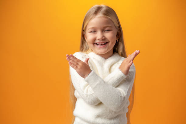 portrait of little child girl with crossed arms against yellow background - flicka, armar kors bildbanksfoton och bilder