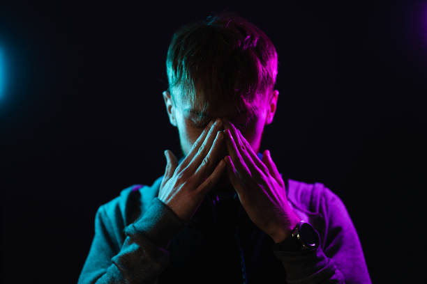 Portrait of man with headphones on neck in neon lights on dark background stock photo