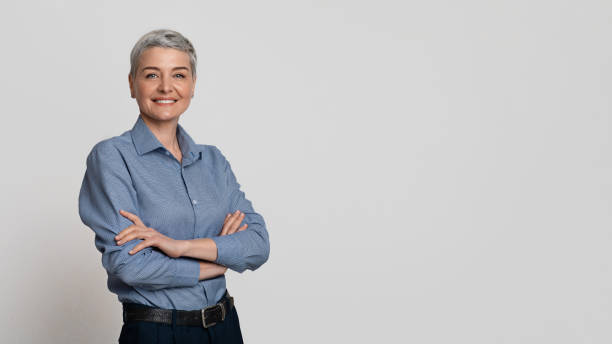 Portrait Of Mature Businesswoman Posing With Folded Arms Over Light Background Portrait Of Mature Businesswoman Posing With Folded Arms Over Light Studio Background, Panorama With Free Space professional portrait stock pictures, royalty-free photos & images