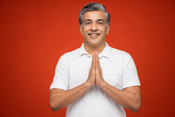 Portrait of mature man standing isolated over red background:- stock photo India, 40-49 Years, Adult, Adults Only, mature men namaste greeting stock pictures, royalty-free photos & images