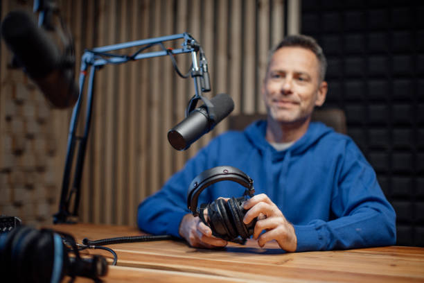 Portrait of mature radio host speaking in microphone while moderating a live show stock photo