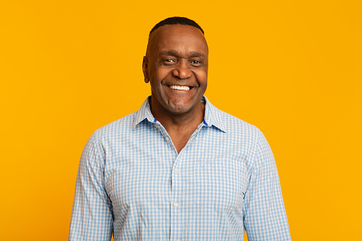 Portrait of middle aged african american man with happy smile, orange background