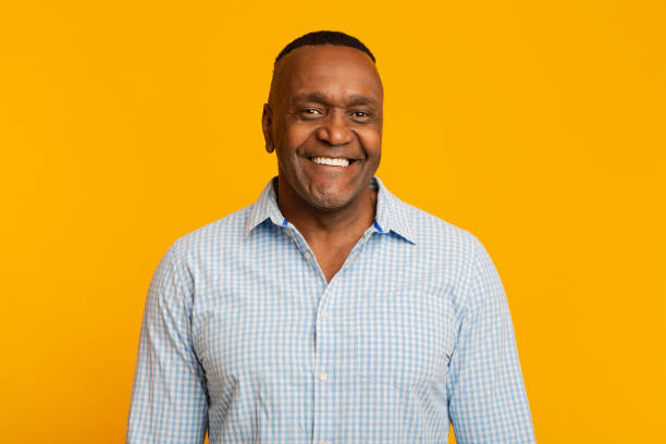 Portrait of middle aged african american man with happy smile Portrait of middle aged african american man with happy smile, orange background mature men stock pictures, royalty-free photos & images