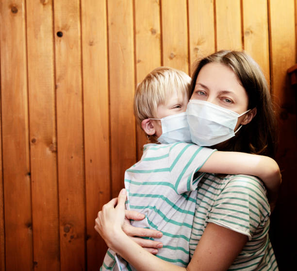 Portrait of mother and son with surgical medical mask 
on wooden background stock photo