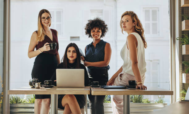 Portrait of multi-ethnic businesswomen together Portrait of four successful young businesswomen together in office. Group of multi-ethnic businesswomen looking at camera. only women stock pictures, royalty-free photos & images