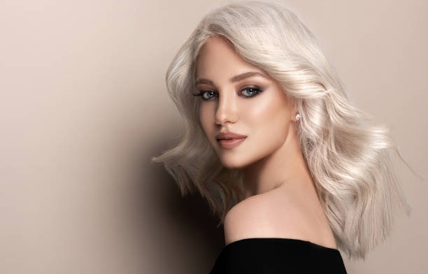 Portrait of nicely looking young model with dyed in the blond shade hair and dressed in a bright make-up.Hairdressing and coloration of hair. stock photo