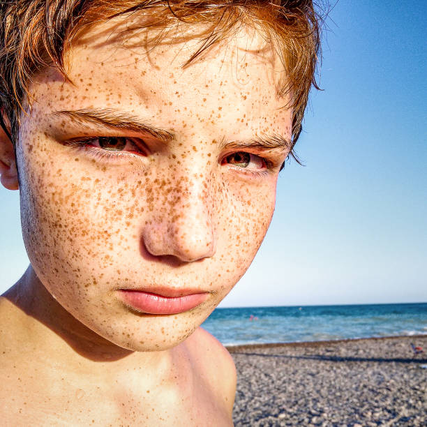 Portrait of red-haired teen boy with freckles on the beach. Close up stock photo