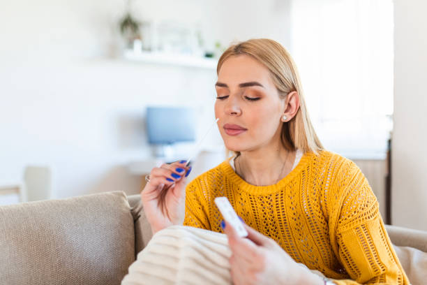 Portrait of relaxed young woman taking a Self-swabbing home tests for COVID-19 at home with Antigen kit. Introducing nasal stick to check the infection of Coronavirus. Quarantine, pandemic. stock photo