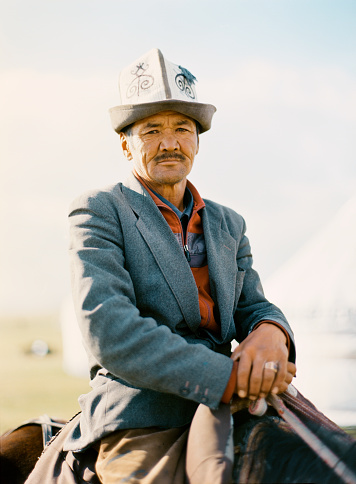 Portrait of Kyrgyzstani senior man on horse near yurt