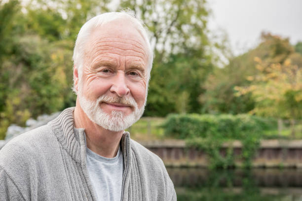Portrait of senior man with white hair and beard smiling Man in his 60s looking towards camera wearing a grey cardigan, focus on head and shoulders 65 69 years stock pictures, royalty-free photos & images