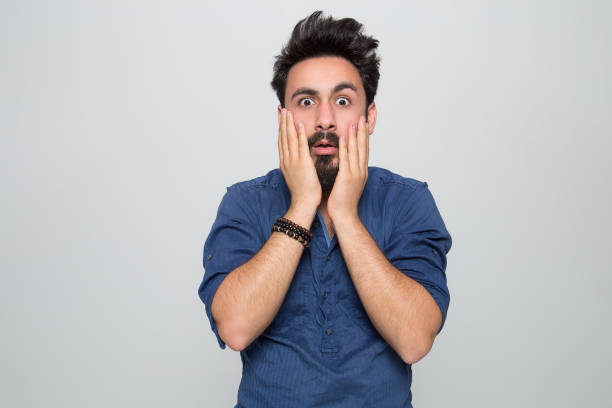 Portrait of shocked young man over grey background Portrait of shocked young man over grey background bad news stock pictures, royalty-free photos & images