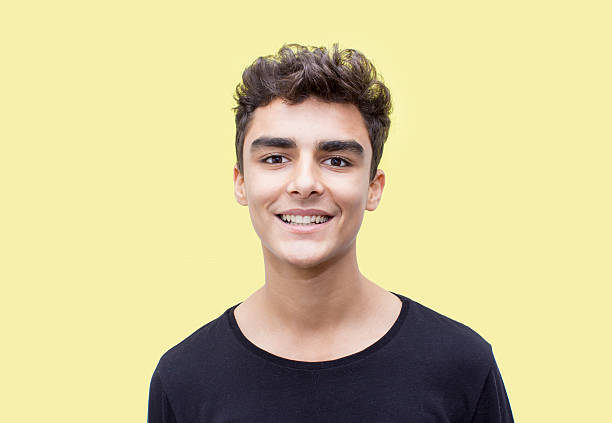 Portrait of smiling boy over yellow background stock photo