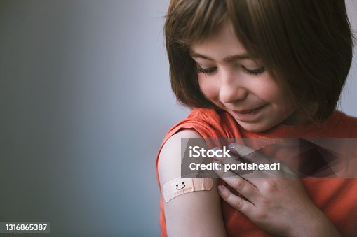 istock Portrait of smiling little child with adhesive bandage on his hand after vaccination 1316865387
