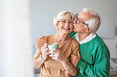 Portrait of smiling senior couple. Cropped portrait of a senior man affectionately embracing his wife at home. Senior man and woman standing in new house looking at camera