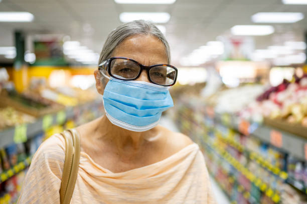 Portrait of Smiling Senior Hispanic Woman Grocery Shopping with Face Mask This is a photograph of a senior Puerto Rican woman looking at the camera and smiling while shopping with a mask on during the pandemic in Orlando, Florida. puerto rican women stock pictures, royalty-free photos & images