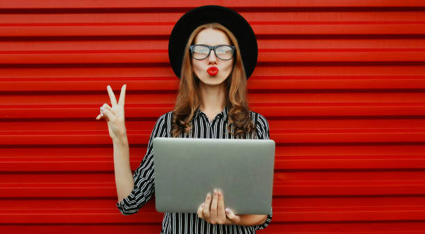 Portrait of stylish young woman with laptop over a red background stock photo