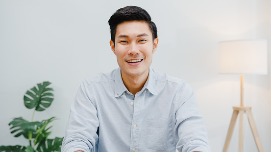 Portrait of successful handsome executive businessman smart casual wear looking at camera and smiling, happy in modern office workplace. Young Asia guy talk to colleague in video call meeting at home.