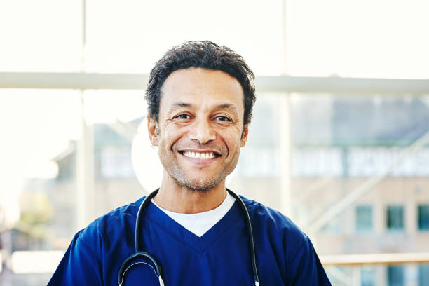 Portrait of successful male surgeon in scrubs Portrait of successful male surgeon with stethoscope around his neck and smiling in hospital nurse face stock pictures, royalty-free photos & images