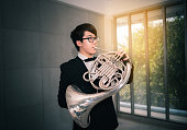 Portrait of teen musician playing instrument classic french horn.