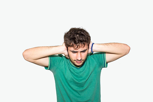 Portrait of teenage boy's hands covering his ears Portrait of teenage boy's hands covering his ears in front of isolated on white. Horizontal shot. Studio shot. Developed from Raw. Young man standing in front of white background and covering his ears with his hands in pain. Fingers in Ears stock pictures, royalty-free photos & images