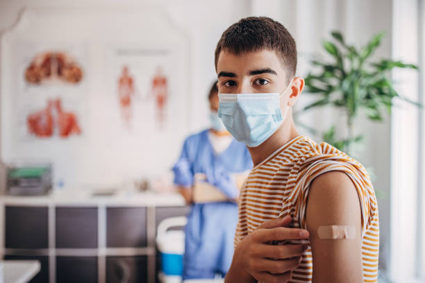 Portrait of teenager patient with band aid on his arm after receiving covid-19 vaccine stock photo