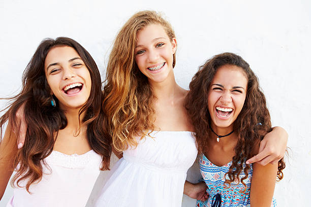 portrait of three teenage girls leaning against wall - alleen tieners stockfoto's en -beelden