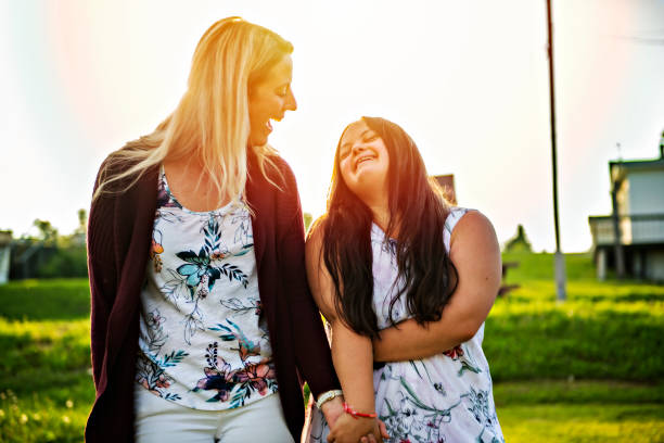 家族の友人と日没時に外で笑顔のトリソミー21大人の女の子の肖像画 - バリアフリー ストックフォトと画像