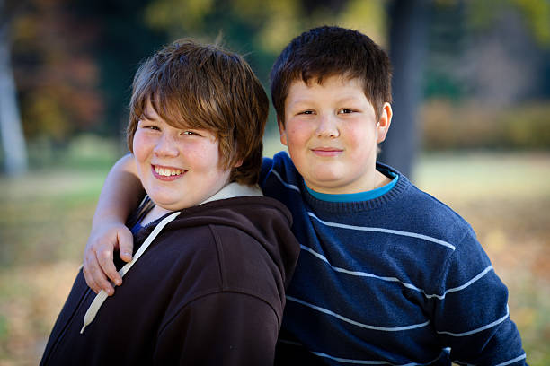 portrait of two cute overweight boys, arms around stock photo
