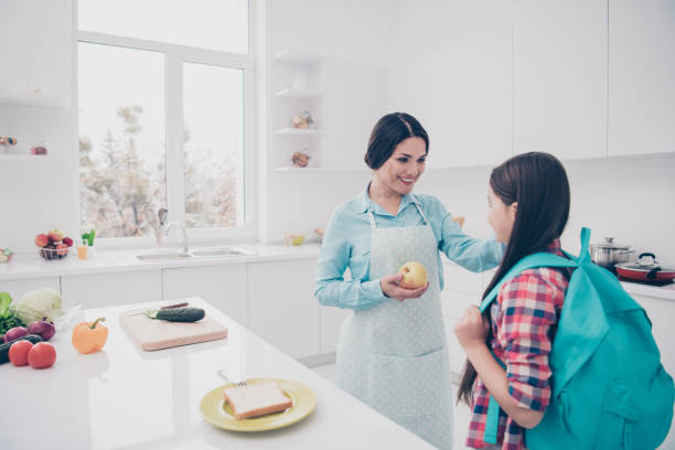 portrait of two nice cute lovely attractive cheerful people mature sweet kind careful mum making giving snack lunch in light white kitchen interior indoors - foster home bag imagens e fotografias de stock