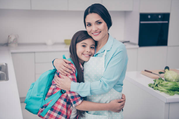 portrait of two nice cute winsome lovely sweet charming attractive cheerful cheery people mature mum cuddling in light white kitchen house interior indoors - foster home bag imagens e fotografias de stock