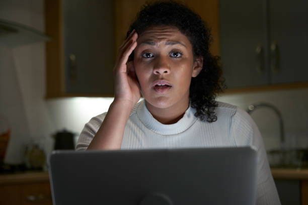 Portrait Of Unhappy Woman At Home With Computer Victim Of Online Crime  victim stock pictures, royalty-free photos & images