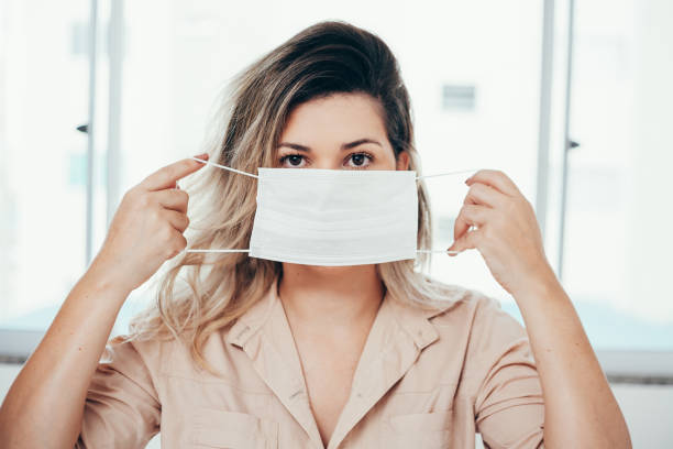 Portrait of woman wearing surgical mask at home. Covid-19, coronavirus and quarantine concept. Portrait of woman wearing surgical mask at home. Covid-19, coronavirus and quarantine concept. surgical mask stock pictures, royalty-free photos & images