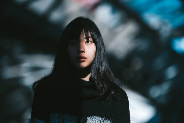 Portrait of young Asian woman A portrait of a young Asian woman while half of her face is lit by the sun and the other half is in the shadow. depression sadness photos stock pictures, royalty-free photos & images