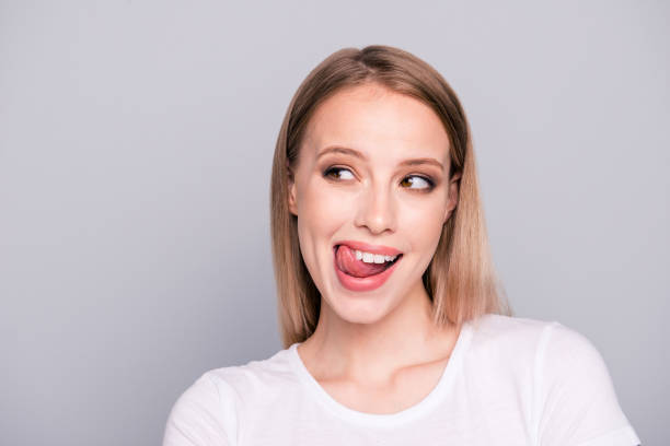 Portrait of young blonde gorgeous caucasian charming girl showing tongue out. Isolated over grey background Portrait of young blonde gorgeous caucasian charming girl showing tongue out. Isolated over grey background healthy tongue stock pictures, royalty-free photos & images