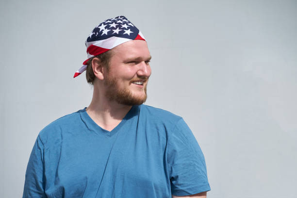 Portrait of young caucasian smiling man with USA flag bandana covered obove his head stock photo