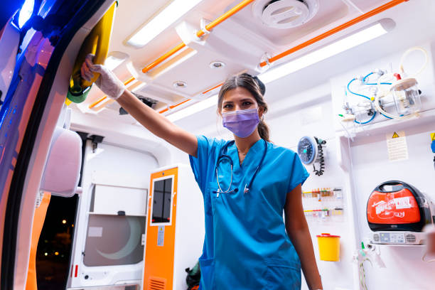 porträtt av ung kvinnlig sjukvårdare med ansiktsmask som arbetar i en ambulans under pandemi - ambulans bildbanksfoton och bilder