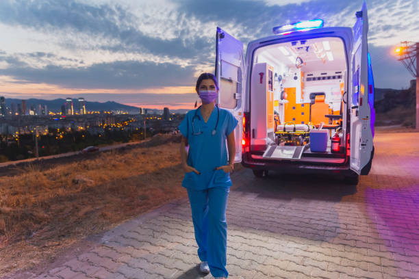 Portrait of young female paramedic with face mask working in an ambulance during pandemic stock photo
