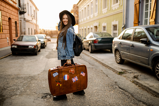 Portrait of young female tourist with retro suitcase