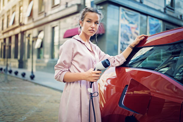 porträtt av ung flicka ladda sin elbil i staden - electric car woman bildbanksfoton och bilder