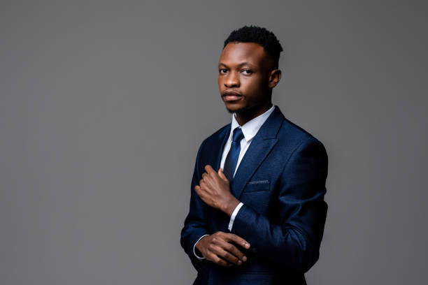 Portrait of young handsome African man wearing formal business suit looking at camera isolated on studio gray background stock photo