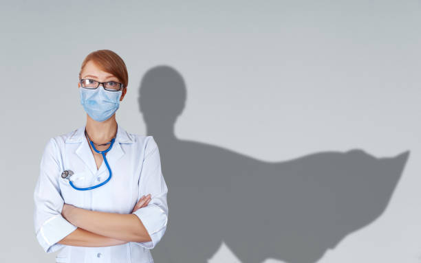 Portrait of young medical doctor with super hero woman cape behind her shoulder Concept of medical doctors fighting against global pandemic virus. Portrait of young medical doctor with super hero woman cape behind her shoulder and medical uniform and mask protect from corona virus outbreak. heroes stock pictures, royalty-free photos & images