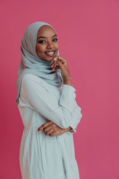 Portrait of young modern muslim afro beauty wearing traditional islamic clothes on plastic pink background. Selective focus stock photo