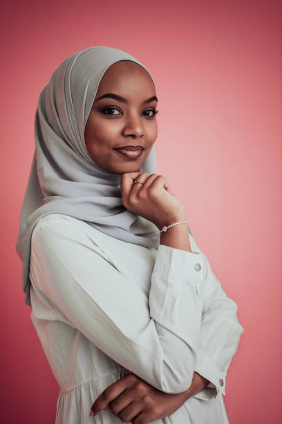 Portrait of young modern muslim afro beauty wearing traditional islamic clothes on plastic pink background. Selective focus stock photo