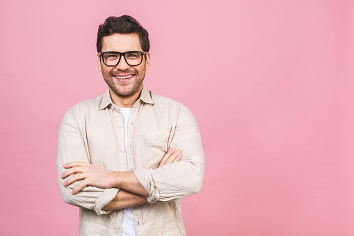 A portrait of young smiling handsome business man in casual shirt isolated on pink background.