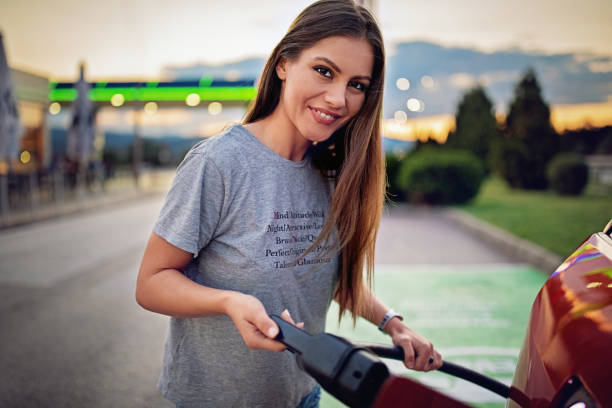 portrait of young woman charging her electric car - electric car woman bildbanksfoton och bilder